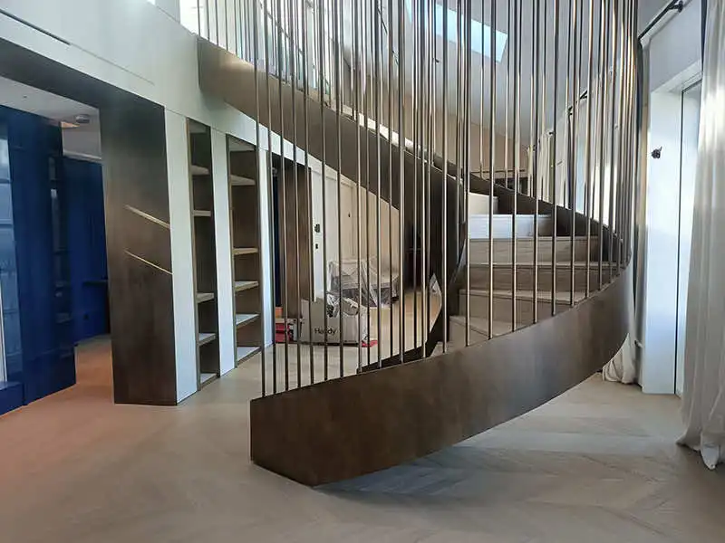 Restauraciones en obra en barandilla de escalera metálica curva con barrotes verticales