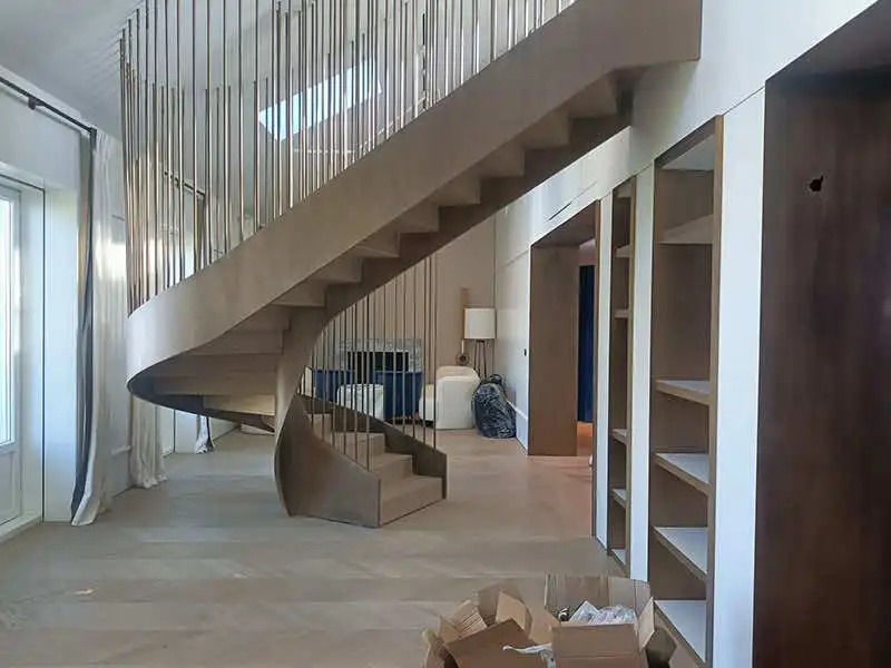 Restauraciones en obra de escalera curva metálica en interior con barrotes verticales