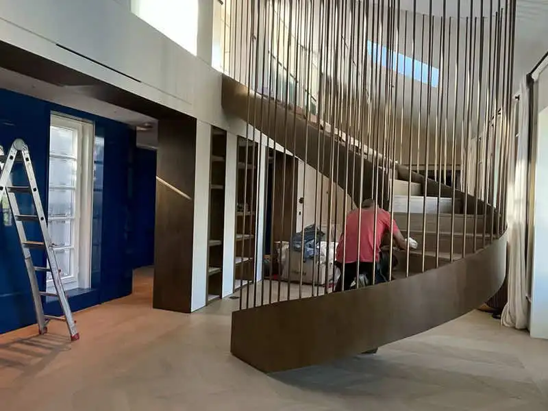 Restauraciones en obra de escalera metálica con operario trabajando en interior de vivienda